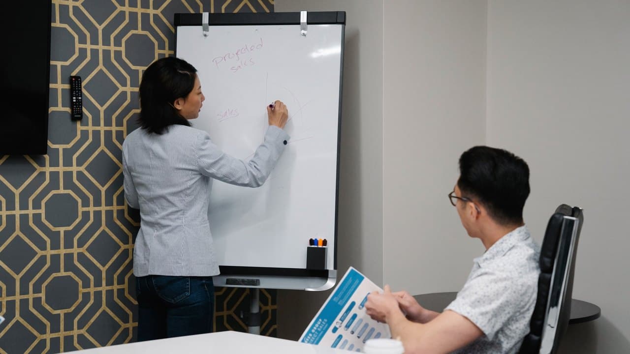 Two colleagues working through a plan drawn on an office whiteboard