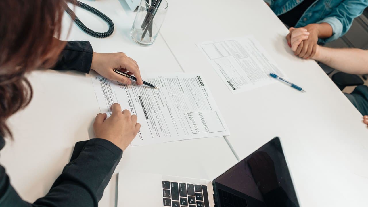 Overhead view of closing paperwork being completed at an office desk