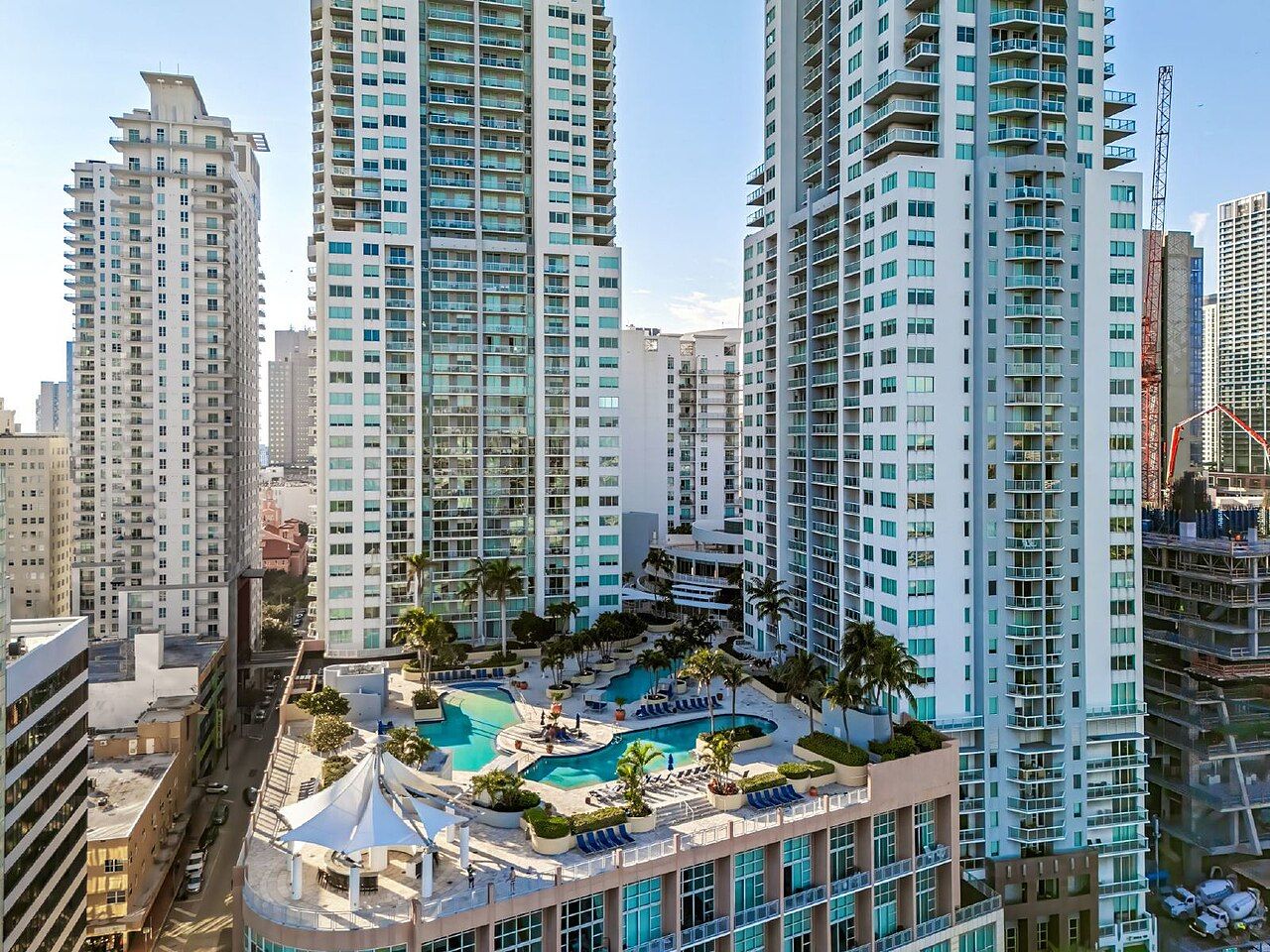 Aerial view of Miami Brickell high-rise condominium towers surrounding a curved pool deck lined with palm trees