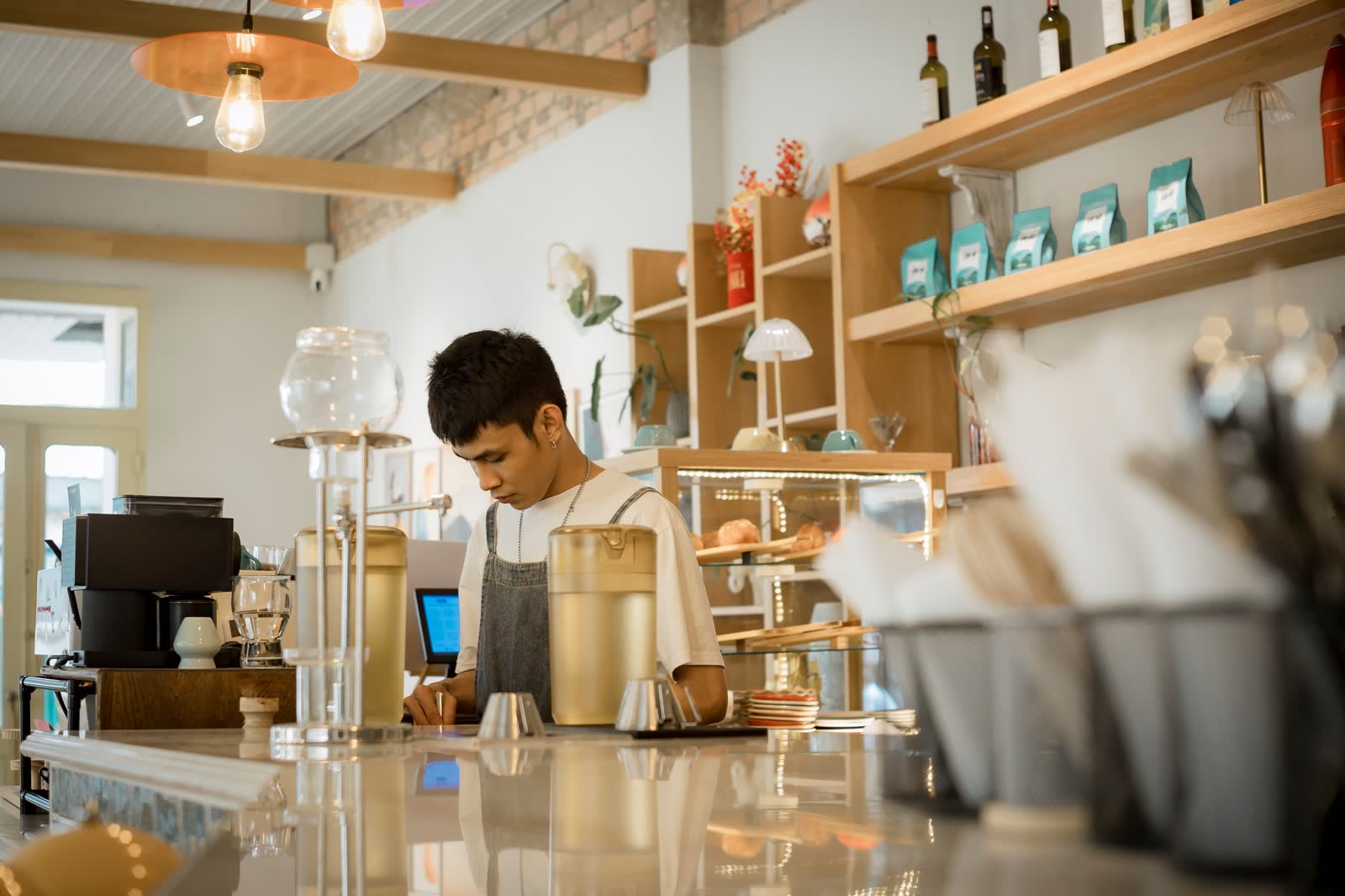 Barista working behind a marble cafe counter under pendant lights