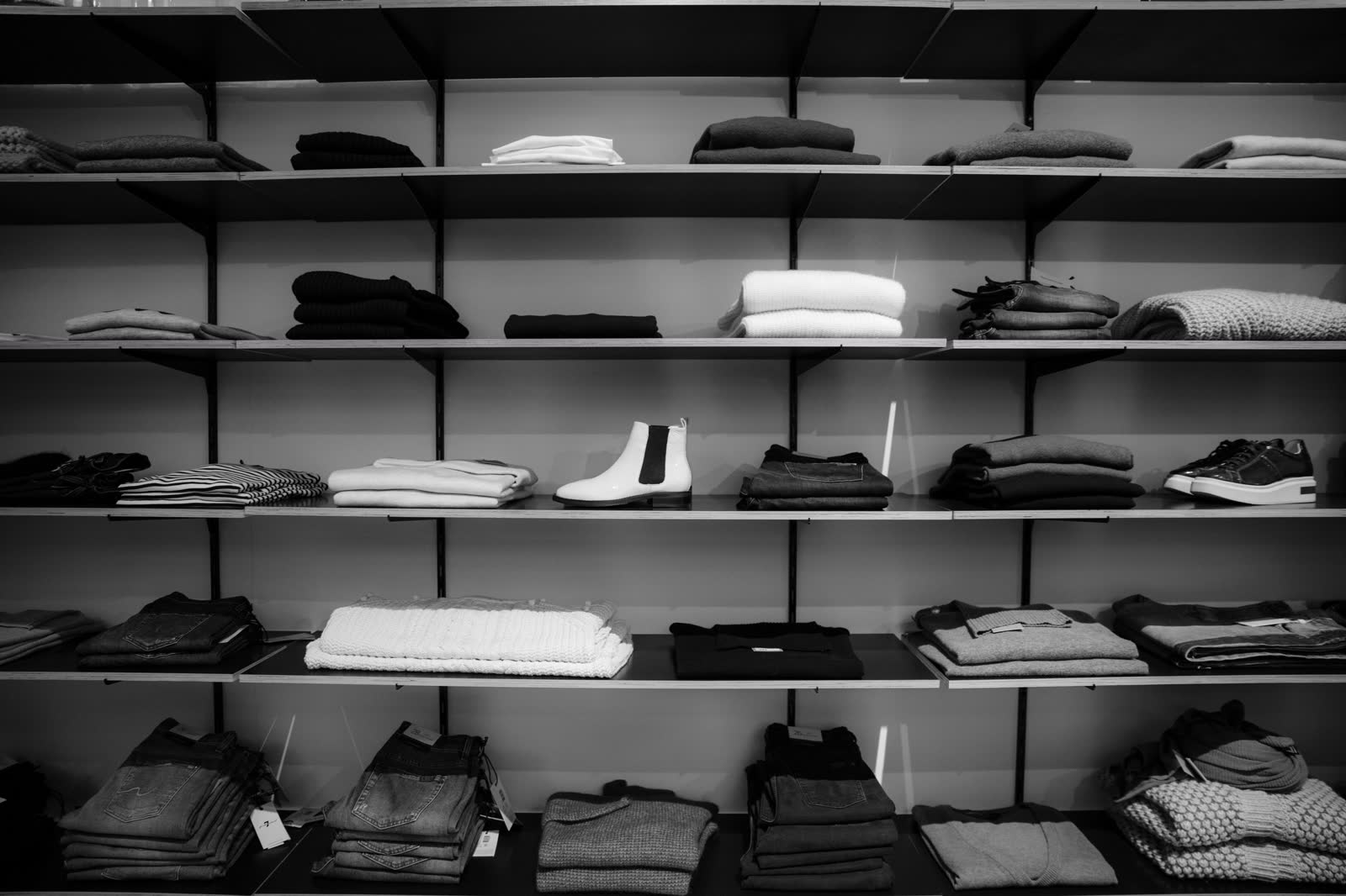 Folded clothing and shoes arranged along the shelves of a small shop