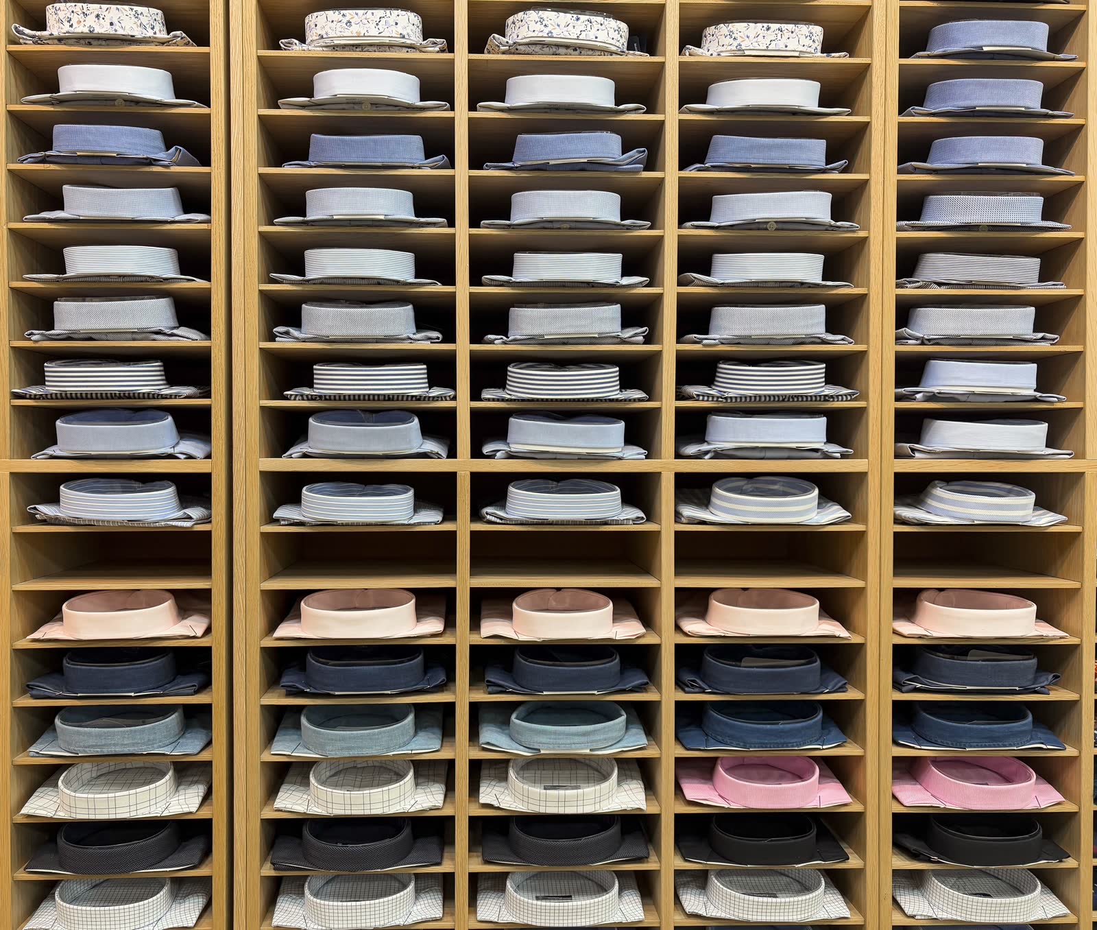 Folded shirts stacked in the pigeonholes of a wooden shop fitting