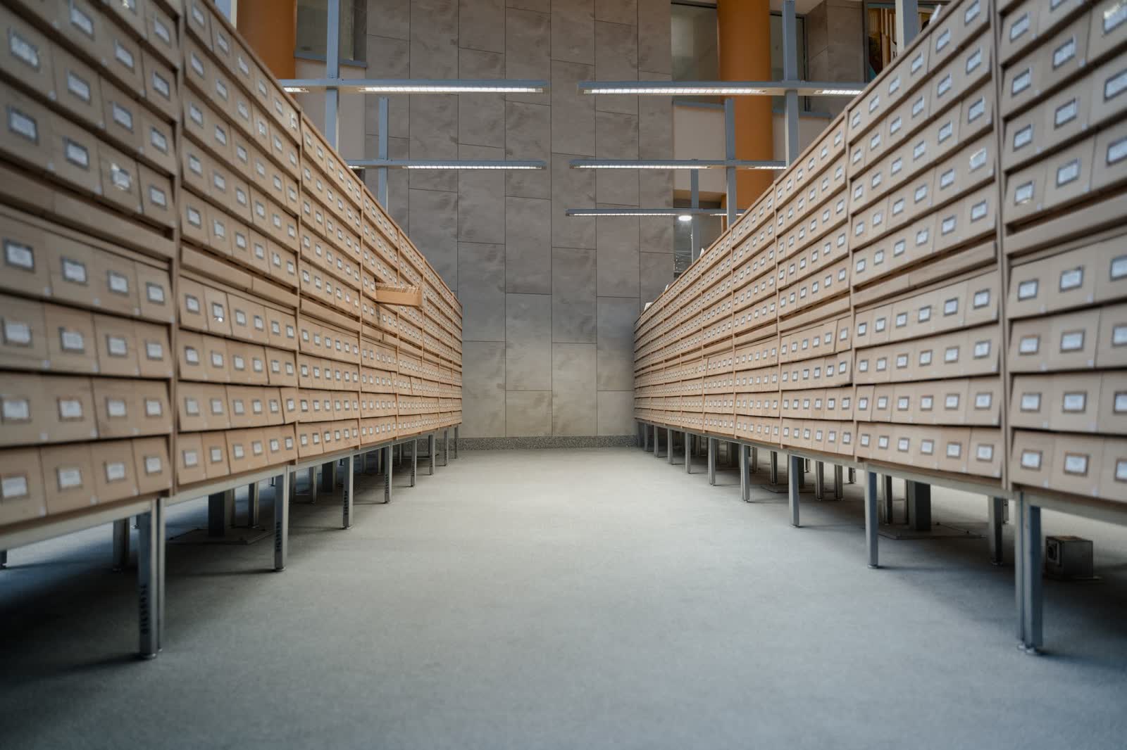 Corridor between two walls of labelled wooden index drawers in an archive