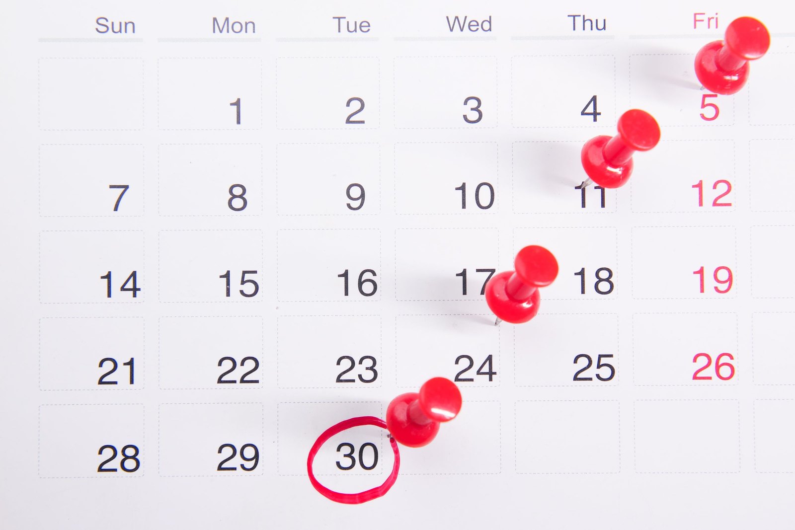 Wall calendar with red pins and the thirtieth circled in red