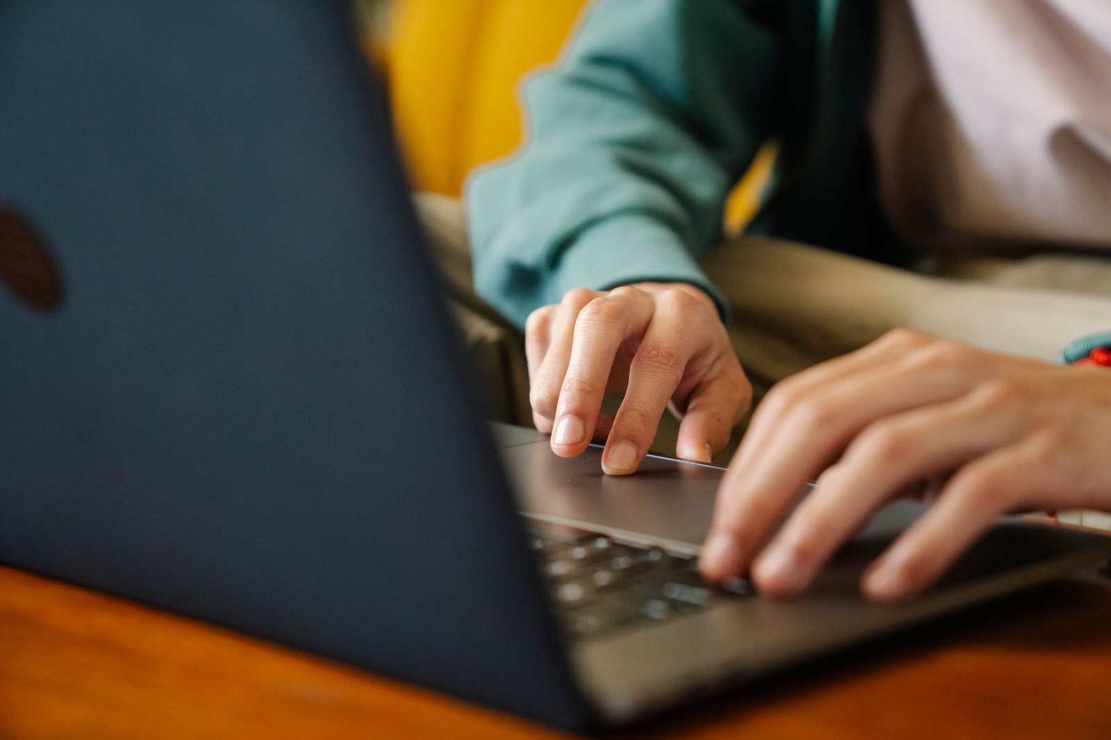 Hands filing a form on a laptop at a bright desk