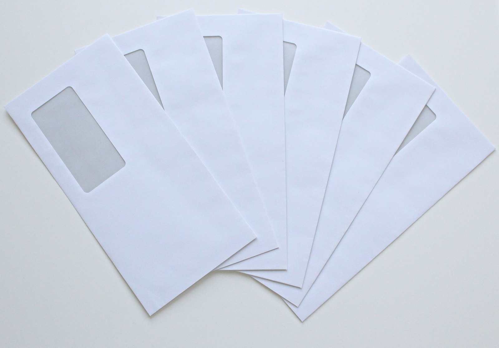 Fan of plain white window envelopes on a pale surface