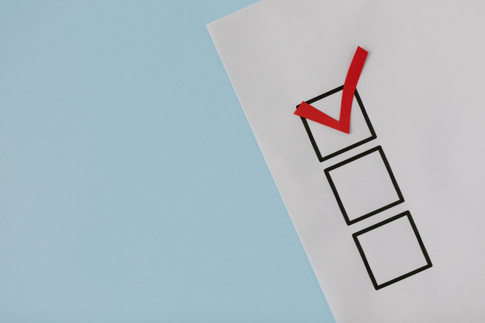 Red check mark drawn in the first of three empty boxes on a sheet of paper