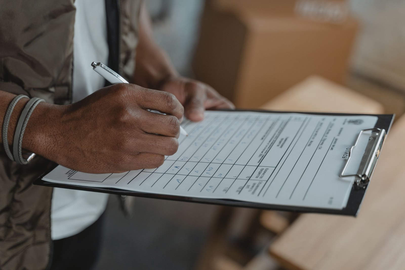 Hands filling in a printed form held on a clipboard