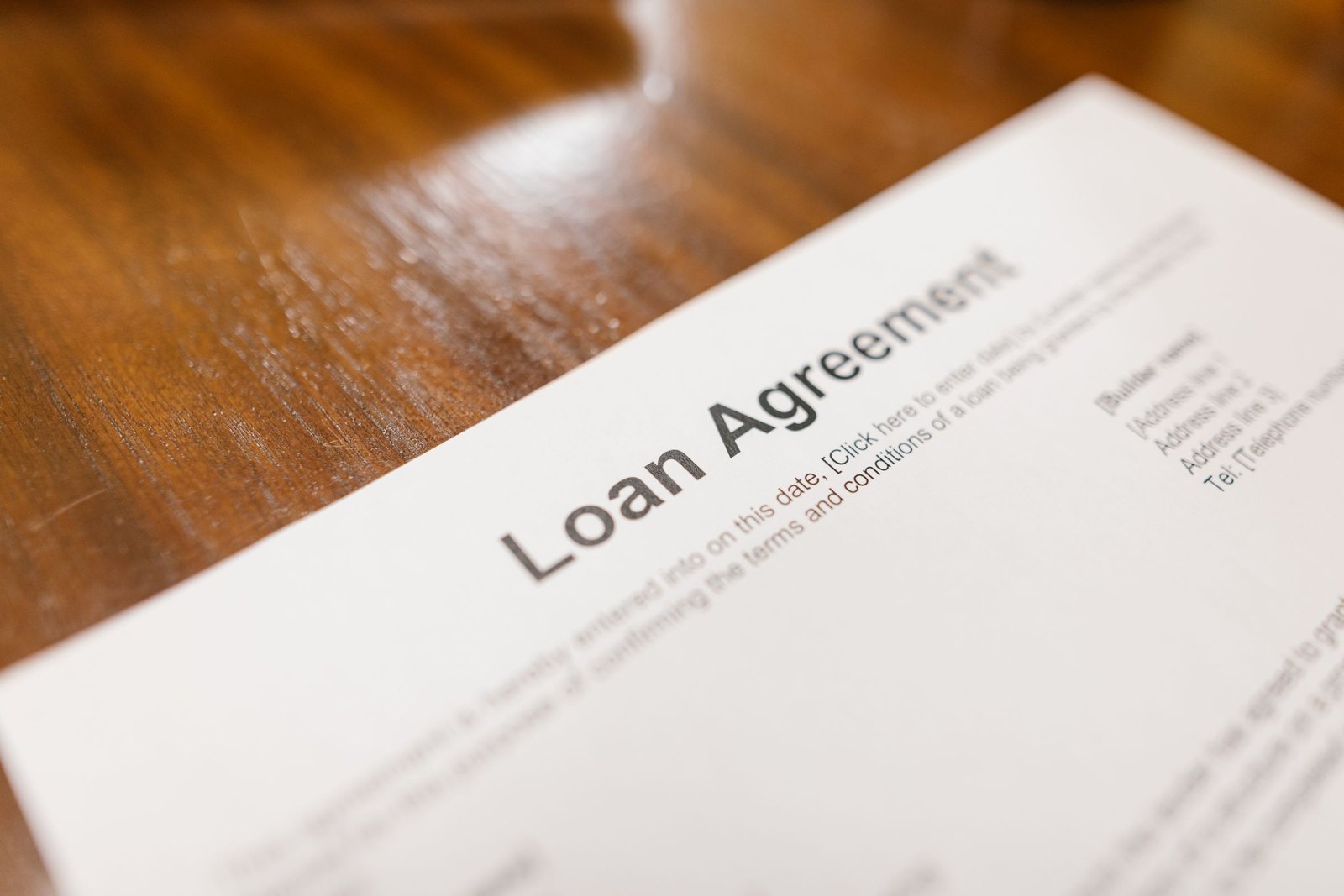 Printed loan agreement lying on a polished wooden desk