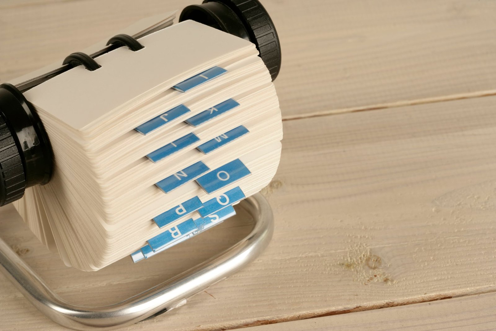 Rotary index-card file open on a wooden desk, tabs marked by letter