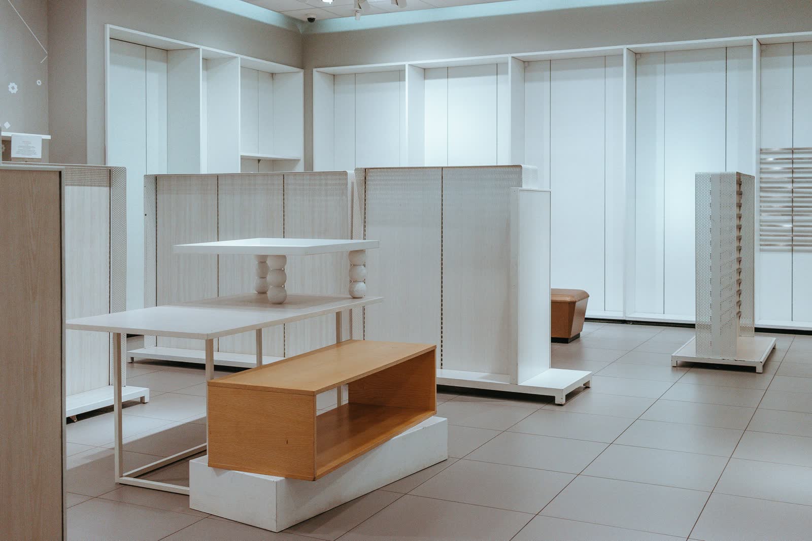 Empty retail unit with bare white shelving and display tables before fit-out