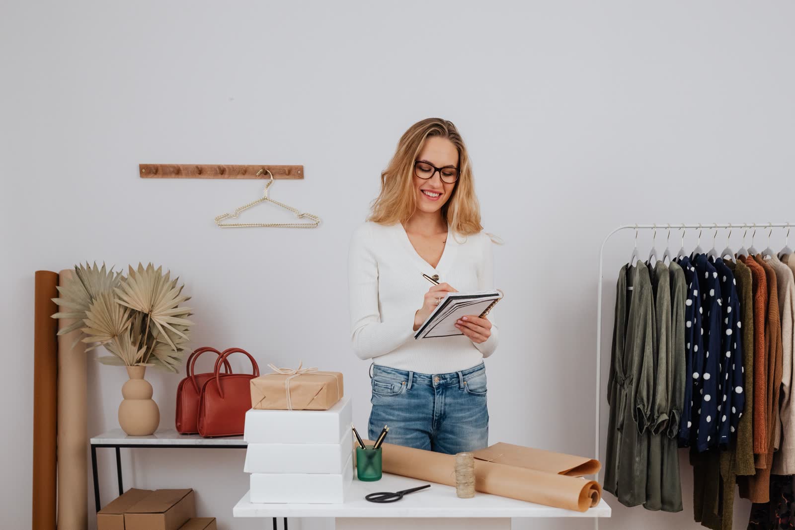 Owner writing in a notebook at a packing table in a newly opened boutique