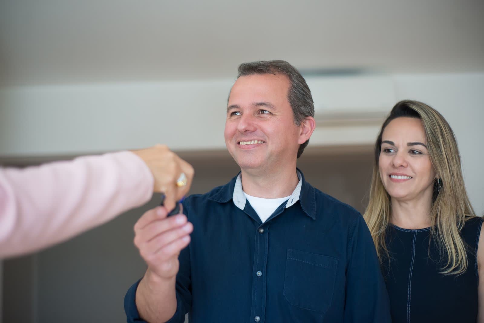 Real estate agent handing keys to a smiling couple