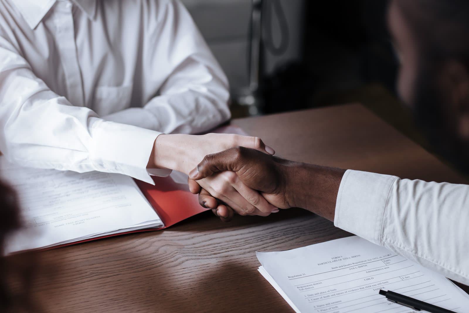 Business handshake over signed documents at a desk