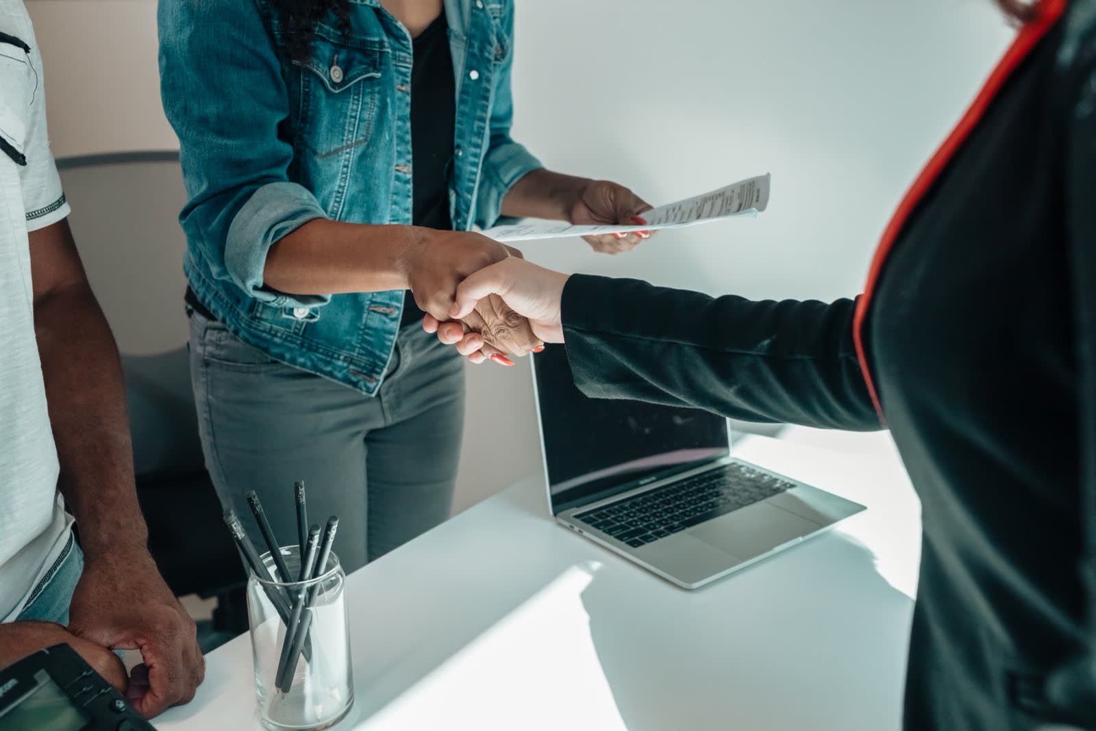 Passing a document across a desk with a laptop nearby