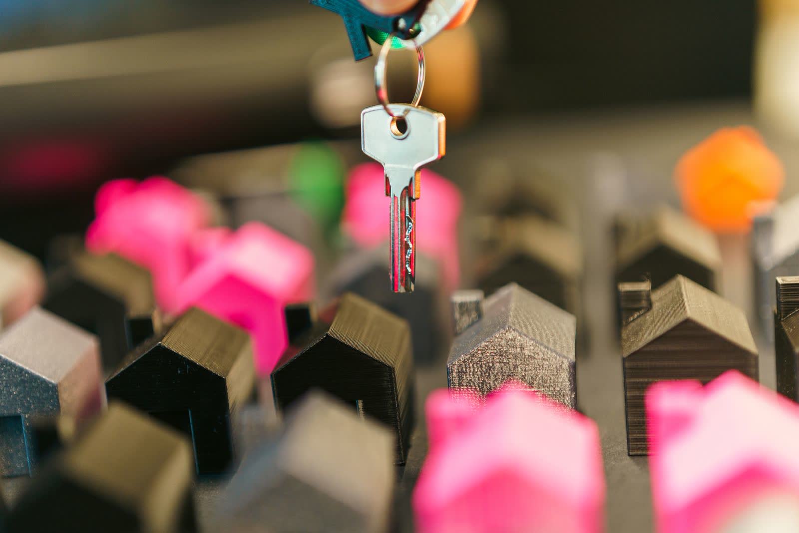 Hand holding a key above miniature house models