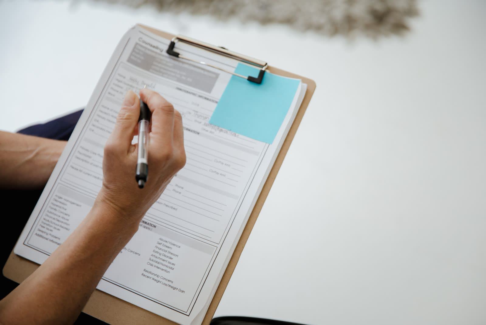 Hands filling out a form on a clipboard