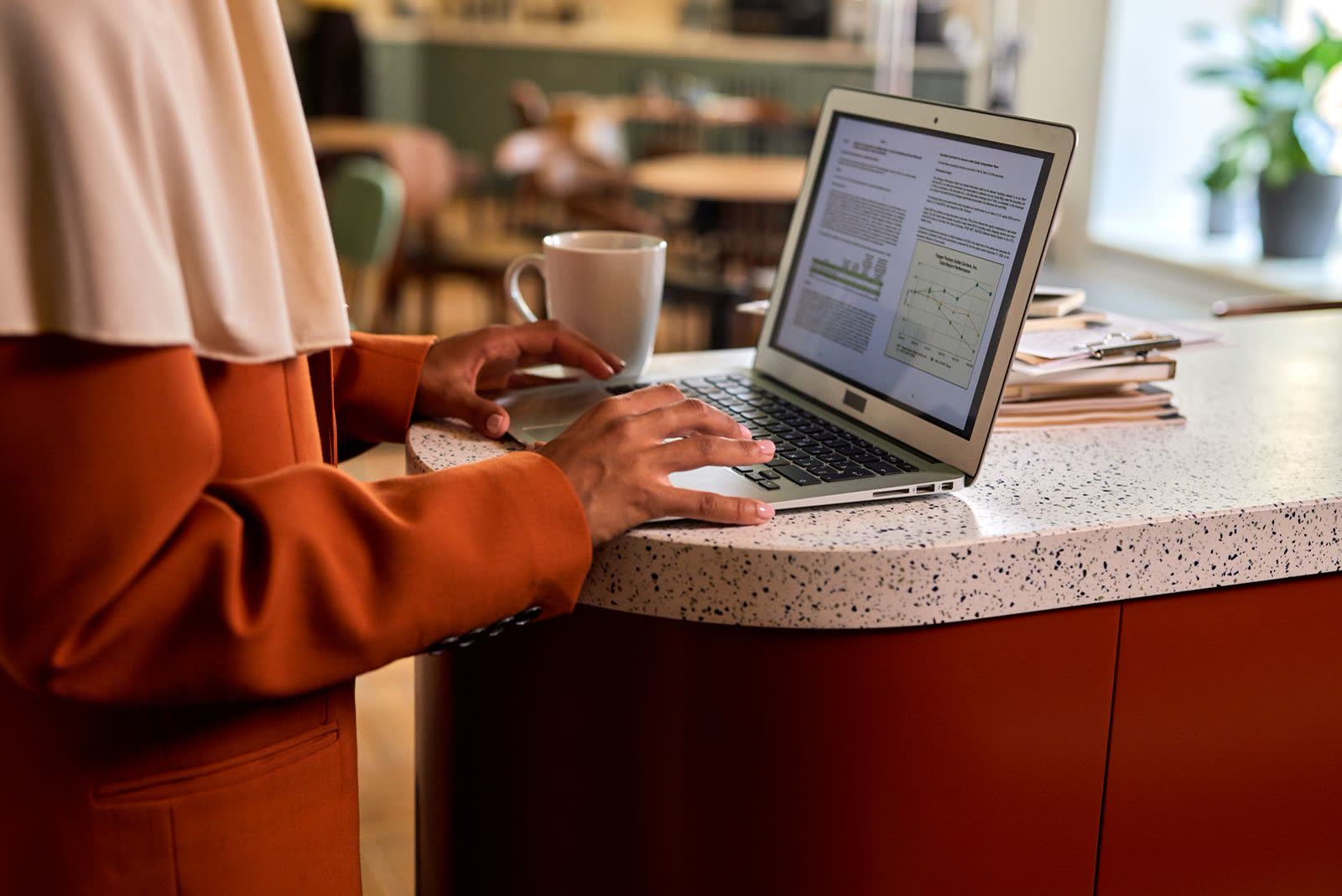 Woman reading research results on a laptop at an office counter