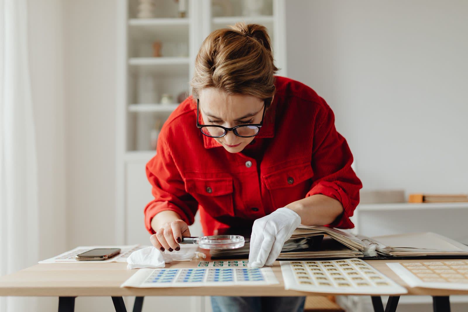 Person examining printed records closely with a magnifier