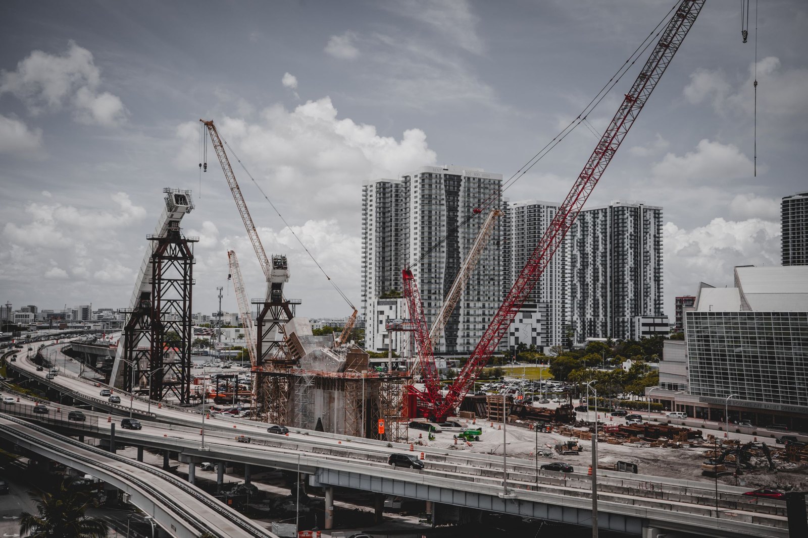 Tower cranes over apartment blocks rising beside a raised highway