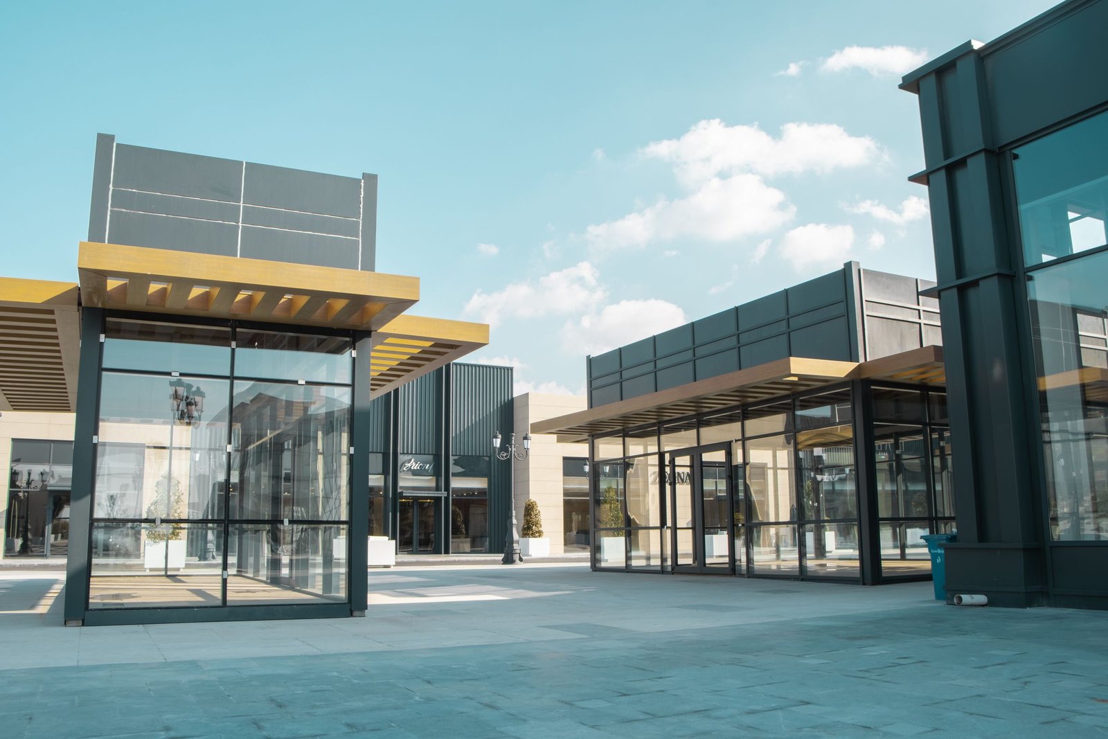 Newly built retail units with glass fronts and no signage yet, under a blue sky